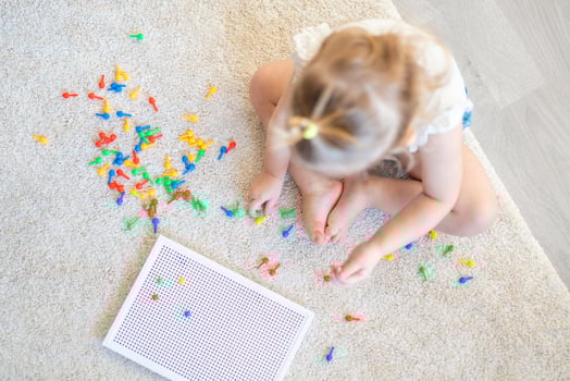 Pretty little girl playing with mushroom nail mosaic at home. Hobby and leisure time photo