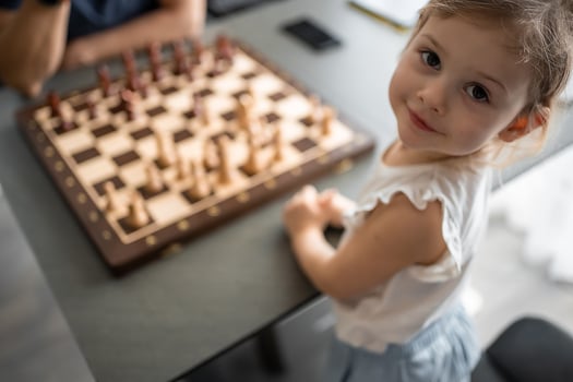 Little girl playing chess with her father at the table in home kitchen. The concept early childhood development and education. Family leisure, communication and recreation. photo