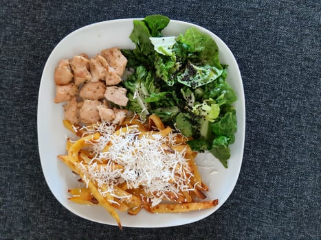 Homemade grilled chicken with french fries, cheese and green salad, served on a white plate photo