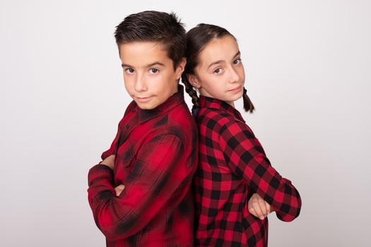 boy and girl with crossed arms posing back to back with challenging look photo