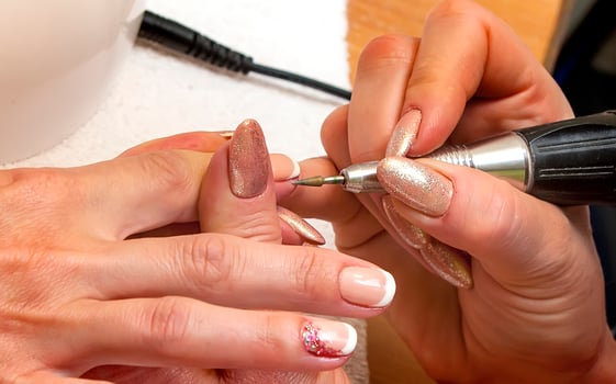 Nail master in rubber gloves make manicure using manicure machine tool photo