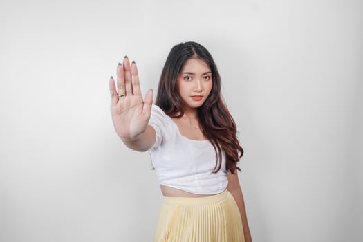 Serious Asian woman wearing casual wear with hand gesture pose rejection or prohibition, isolated by white background photo