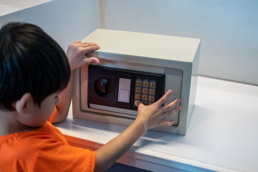 Little Asian boy opening safe at home photo