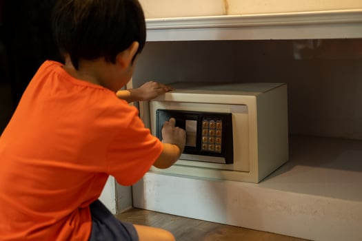 Little Asian boy opening safe at home photo