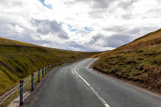 Curving road through a hilly landscape under a cloudy sky in Yorkshire Dales. photo