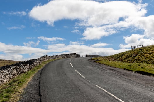 Empty country road with stone walls under a blue sky with clouds in Yorkshire Dales. photo