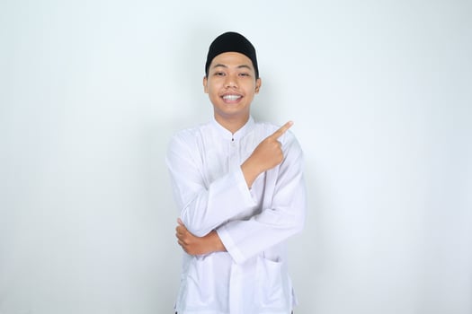 happy muslim asian man pointing to side isolated on white background photo
