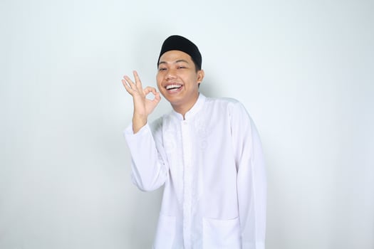 smiling asian man muslim show ok signs isolated on white background photo