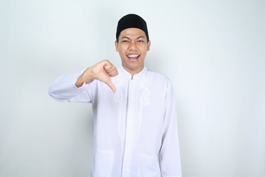 funny muslim asian man giving thumbs down isolated on white background photo