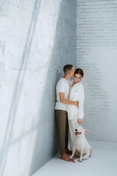 young couple guy and girl in a bright room playing with pet photo