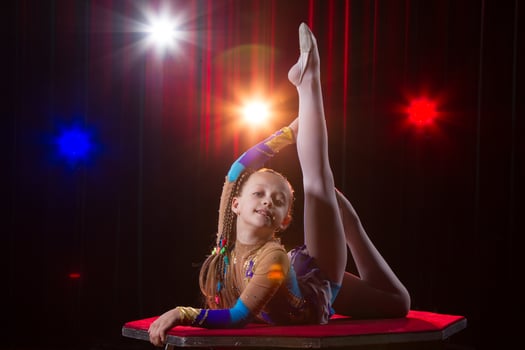 A girl with a flexible body. Performs a circus artist. Circus gymnast. Balancing act. The child performs an acrobatic trick photo