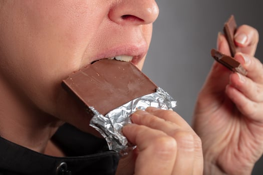 A woman, whose face is not visible, eats a chocolate bar. photo