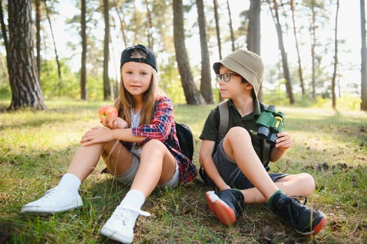 boy and girl go hiking with backpacks on forest road bright sunny day photo