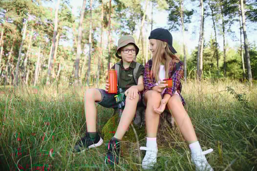 boy and girl go hiking with backpacks on forest road bright sunny day photo