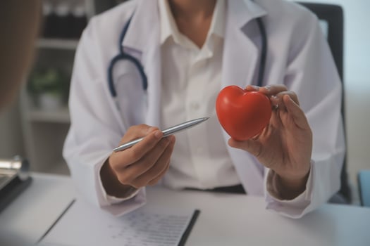 Hands of doctor woman holding red heart, showing symbol of love, human support to patient, promoting medical insurance, early checkup for healthcare, cardiologist help. Close up of object photo