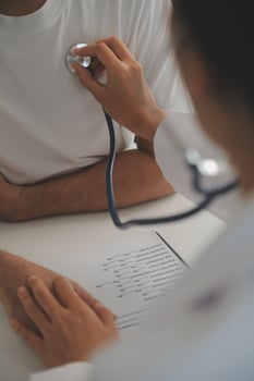Young doctor is using a stethoscope listen to the heartbeat of the patient. Shot of a female doctor giving a male patient a check up photo