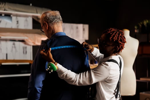 Expert seamstress sizing up stylish client proportions for upcoming luxurious bespoke costume. Elderly customer getting measurements taken by meticulous suitmaker in tailoring studio photo