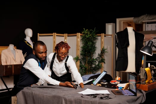 High end manufacturing suitmakers cutting textile material with scissors in tailoring studio, designing sartorial fashion clothes. Dressmakers working on bespoke client comission photo
