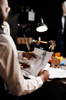 Tailoring studio workspace collegues brainstorming best adjustments to be made on premium quality bespoke dress to be made for client. Dressmakers using sketch drawing to design sartorial garment photo