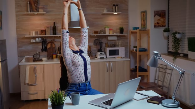 Exhausted remote employee streching while working on a deadline late at night. Busy focused freelancer using modern technology network wireless doing overtime for job reading writing, searching photo