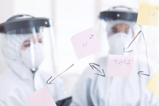 Stomatologs dressed in ppe suit during covid-19 as safety precaution. Medical team in stomatology office wearing coverall in dental office writing ideas on sticky notes. photo