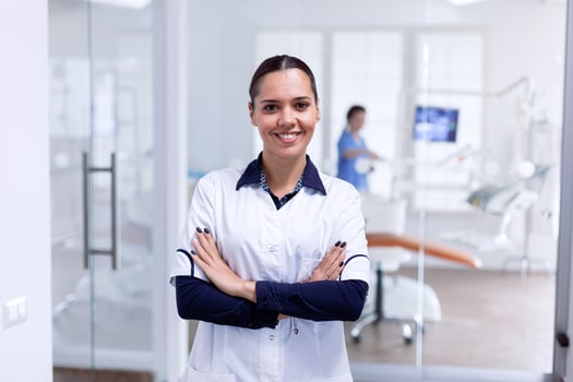 Portrait of stomatology medic in dental reception with arms crossed looking at camera wearing uniform. Happy smiling dentist in her orthodontic office. photo