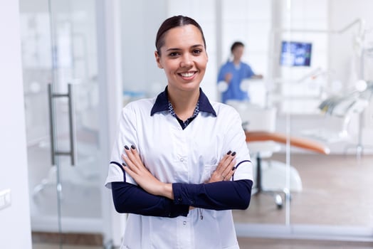 Portrait of cheerful dentist in dental reception with arms crossed looking at camera wearing uniform. Happy smiling dentist in her orthodontic office. photo