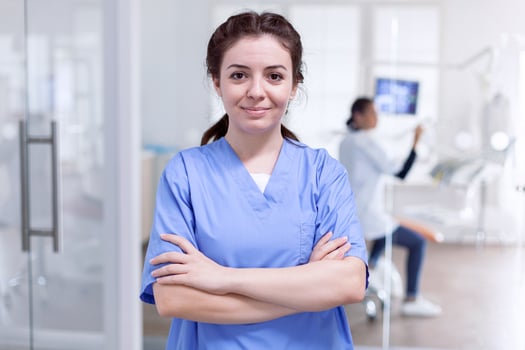 Portrait of stomatology nurse in dental reception with arms crossed looking at camera wearing uniform. Happy smiling assistant in orthodontic office. photo