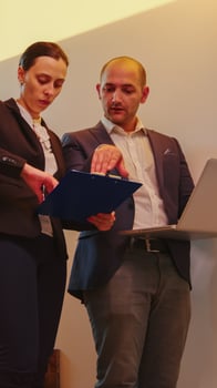 Businesswoman talking with corporate executive manager on staircase of business building looking on laptop. Professional successful entrepreneur in team working overtime in modern office stairs. photo