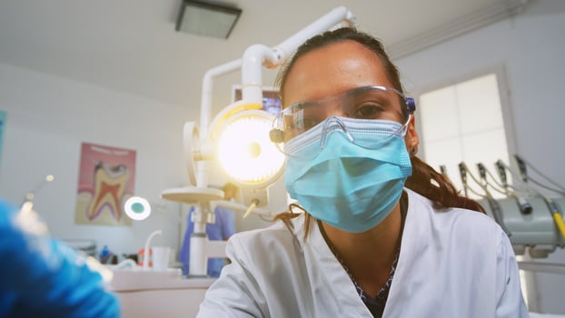 Patient pov visiting dental clinic for surgery treating affected mass. Doctor and nurse working together in modern orthodontic office, lighting the lamp and examining person wearing protection mask. photo