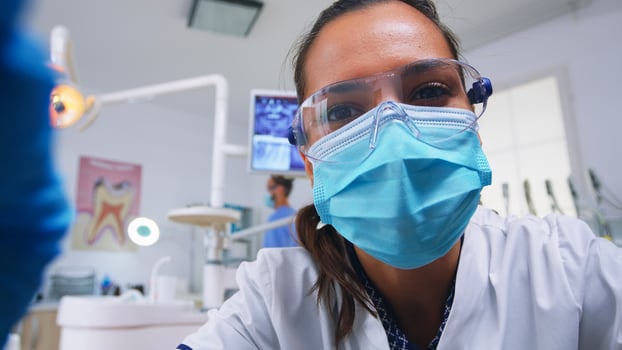 Pov of dentist working on patient mouth hygine in dental office checking teeth problems. Doctor examining in orthodontic office with light lamp and sterilized utensils, close-up face in medical mask. photo