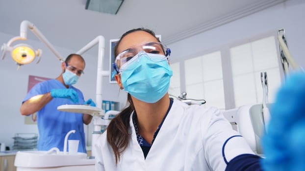 Dentist technician drilling patient tooth in dental clinic, person pov. Doctor with mask holding tools examining woman with toothache sitting on stomatological chair, nurse preparing tools for surgery photo