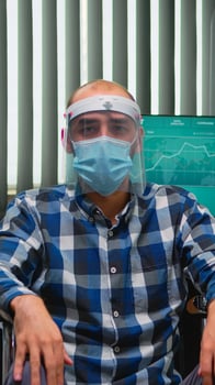 Handicapped businessman in wheelchair with mask having online conference in business office during covid-19 pandemic. Immobilized freelancer working in financial company respecting social distance. photo