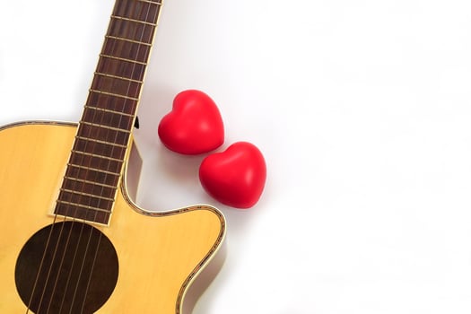 Acoustic guitar neck and red heart against white background. Love, relax and music concept. photo
