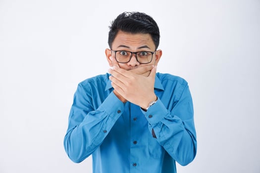 asian businessman covered his mouth with both hands with glasses wearing blue shirt isolated on white background photo