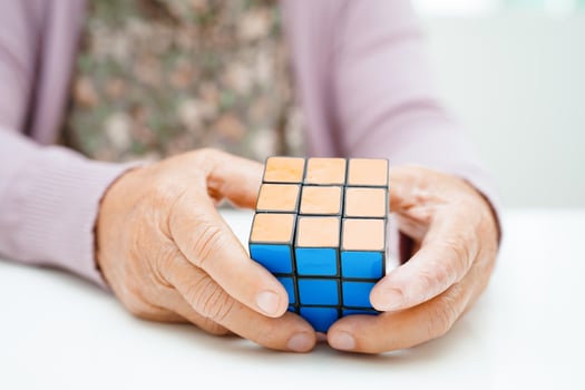 Bangkok, Thailand - May 15, 2022 Asian elderly woman playing Rubik cube game for treatment dementia prevention and Alzheimer disease. photo
