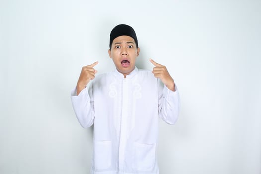 asian man muslim pointing him self with shocked face expression isolated on white background photo