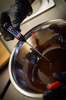 Woman cooking tasty melted chocolate on table in kitchen. photo