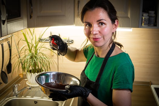 Woman cooking tasty melted chocolate on table in kitchen. photo