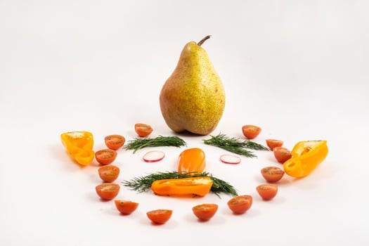 The face of a man made of sliced vegetables and a pear on his head on a white background photo