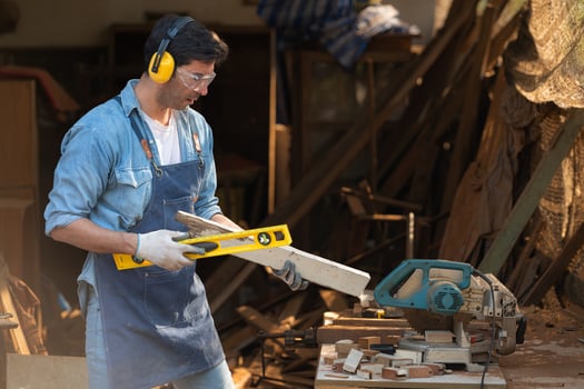 Portrait of a carpenter holding a spirit level in his workshop. photo