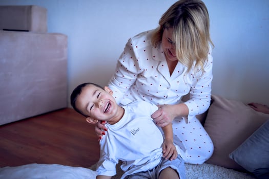 a mother plays and drags her little son on a sheet around the room photo