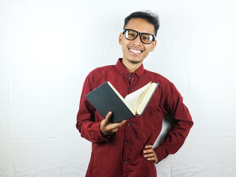 Handsome Asian business man smiling and holding and reading book in hand photo