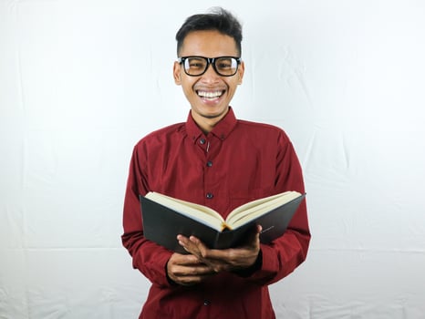 Handsome Asian business man smiling and holding and reading book in hand photo