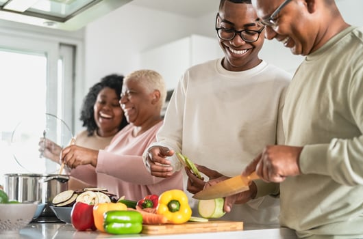 Happy African family having fun in modern kitchen preparing food recipe with fresh vegetables - Food and parents unity concept photo