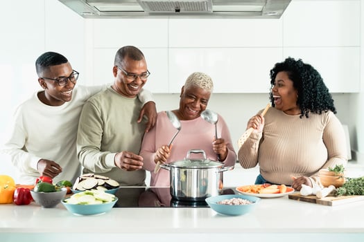 Happy black family having fun cooking together in modern kitchen - Food and parents unity concept photo