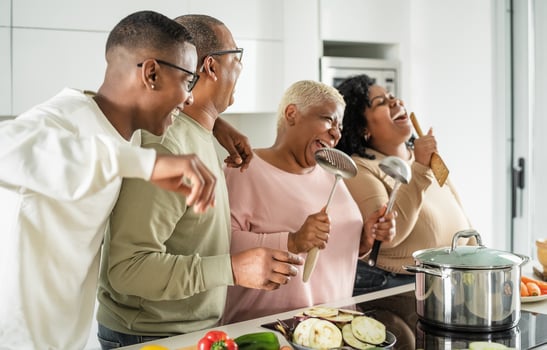 Happy black family having fun cooking together in modern kitchen - Food and parents unity concept photo