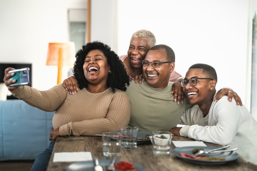 Happy black family having fun taking selfie with mobile smartphone cam while having lunch at home photo