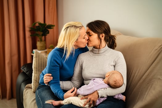 Happy lesbian couple having tender moments with their small baby at home - Family and materhood concept photo