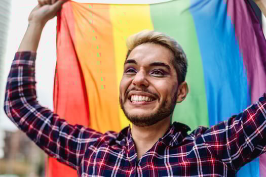 Happy gay man celebrating pride festival holding rainbow flag symbol of LGBTQ community photo
